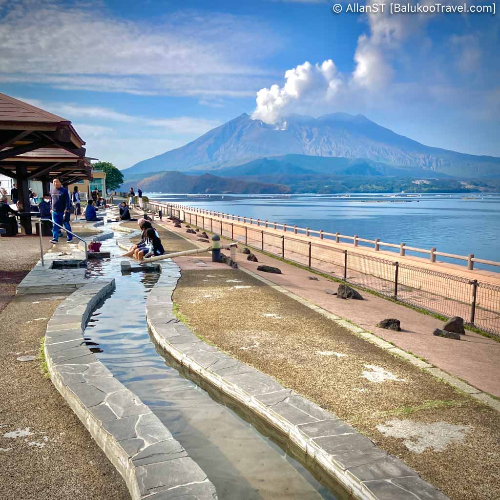 Tarumizu Yuttarikan Roadside Station. Free outdoor hot spring foot bath by the sea, allowing visitors to unwind and admire the beauty of the area (Sakurajima volcano in background) while soaking their feet.
