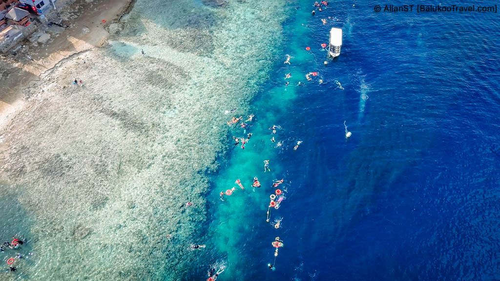 Aerial view of Panagsama Beach with snorkelers. The dark patches off the underwater cliffs (dropoff) is the sardine run. 
