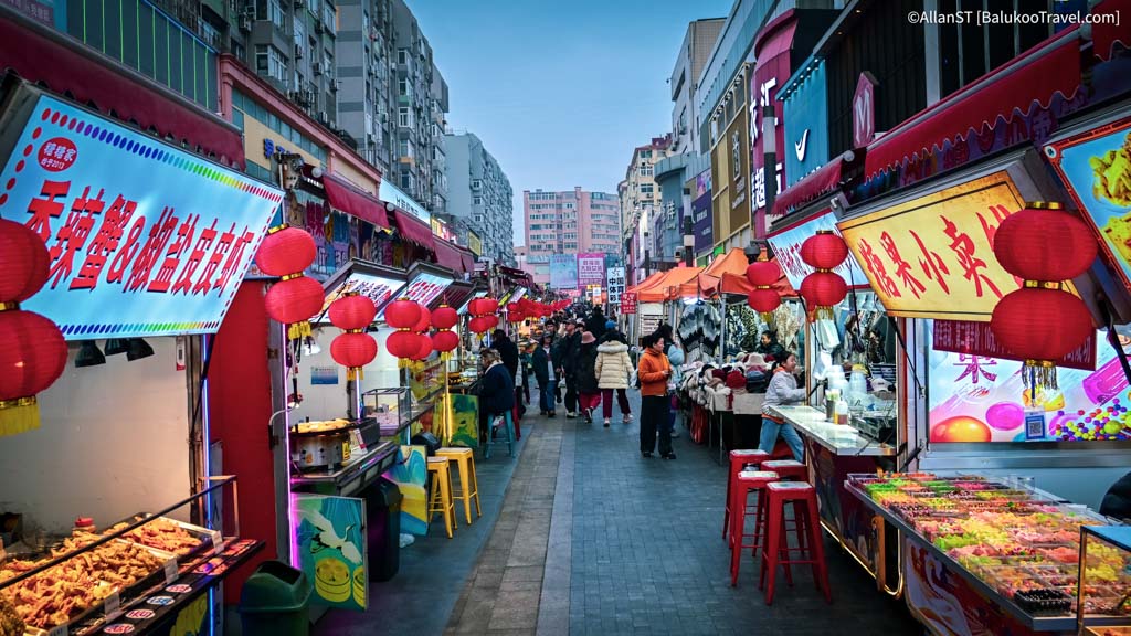 This bustling market area is packed with street food stalls, snack vendors, and shops selling clothing and souvenirs.